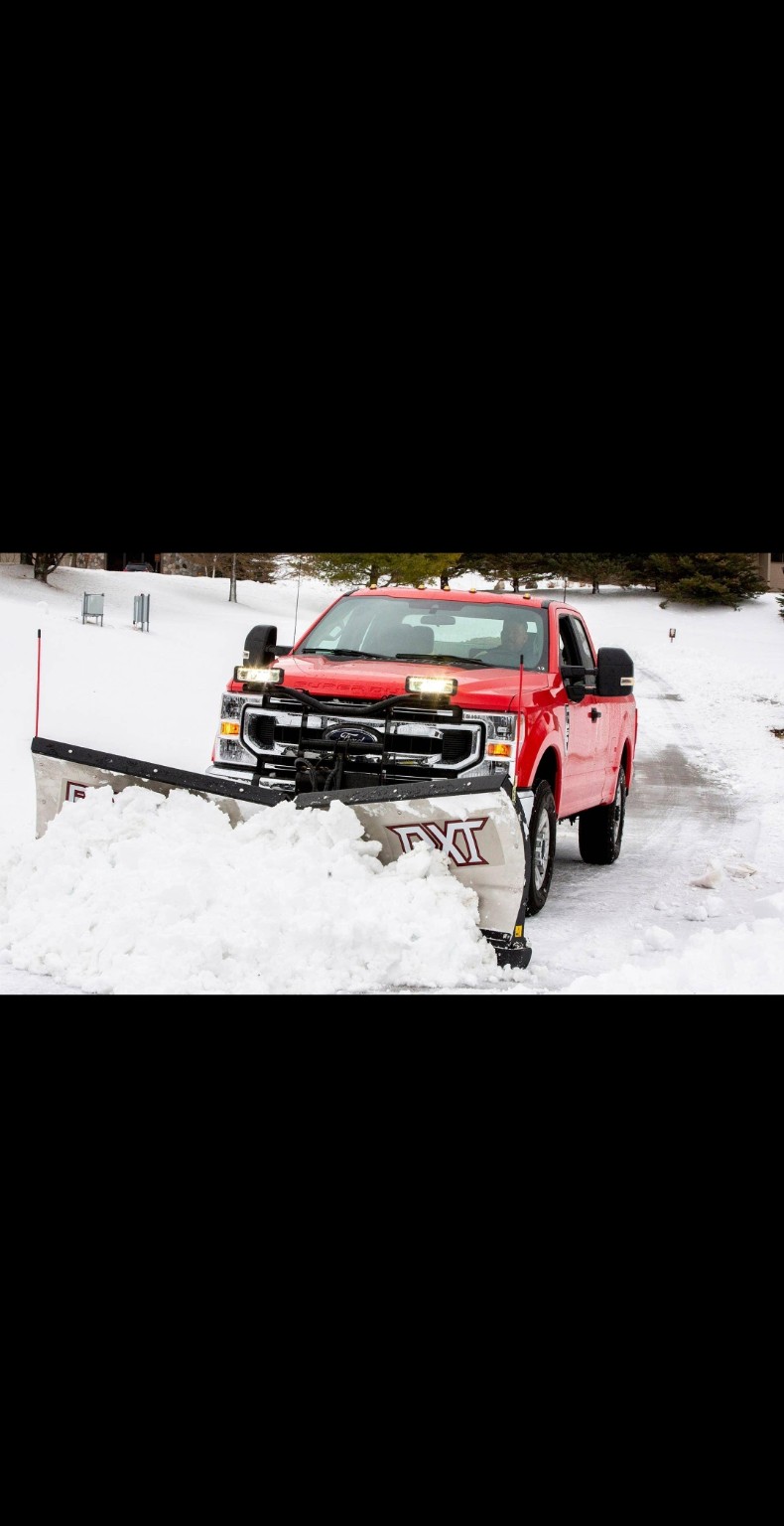 Red plow truck clearing heavy snow